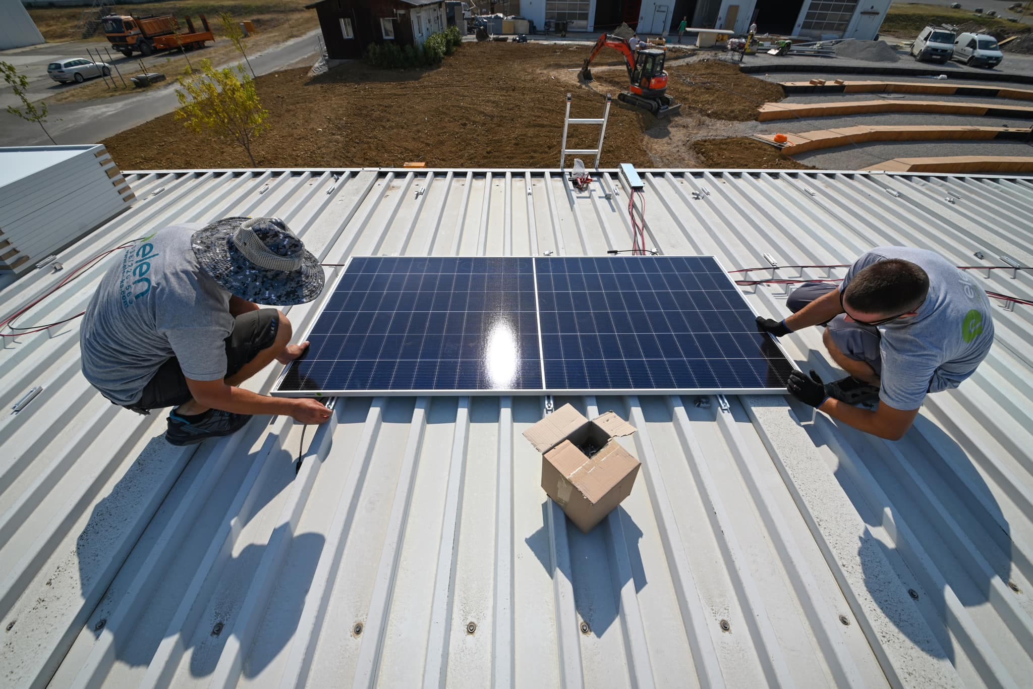 Two Elen technicians mounting a solar panel on the hangar roof